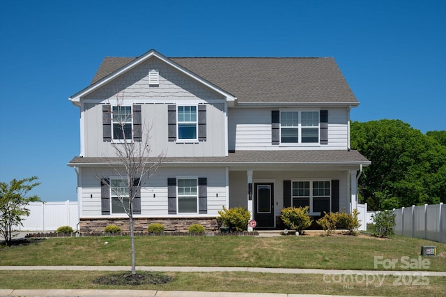 view of front of house with fence, a porch, a front yard, and stone siding