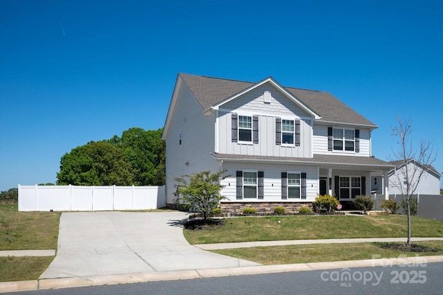 traditional-style house with fence, board and batten siding, driveway, and a front yard