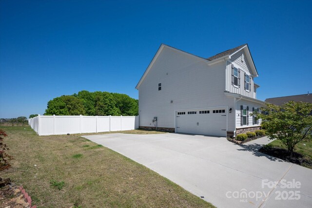 view of property exterior with driveway, a yard, an attached garage, and fence