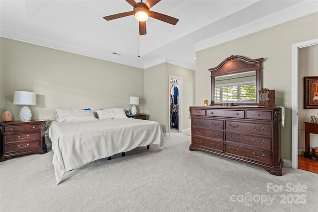bedroom featuring light carpet, a walk in closet, a closet, crown molding, and baseboards