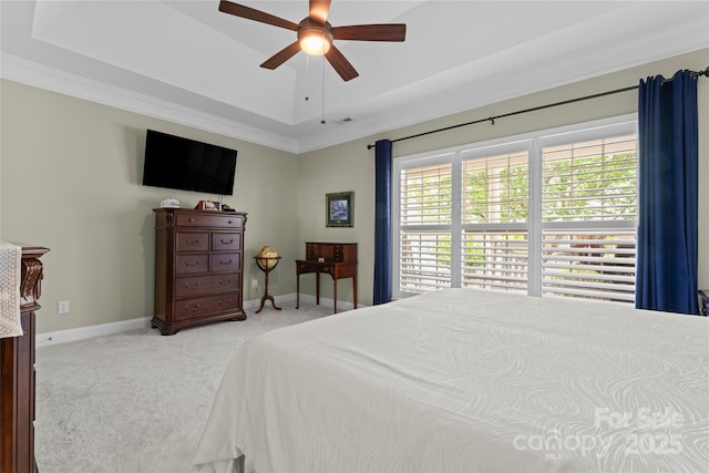 bedroom with a tray ceiling, carpet, crown molding, and baseboards