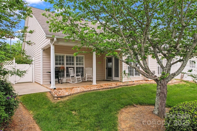 back of property with fence, a patio area, roof with shingles, and a yard