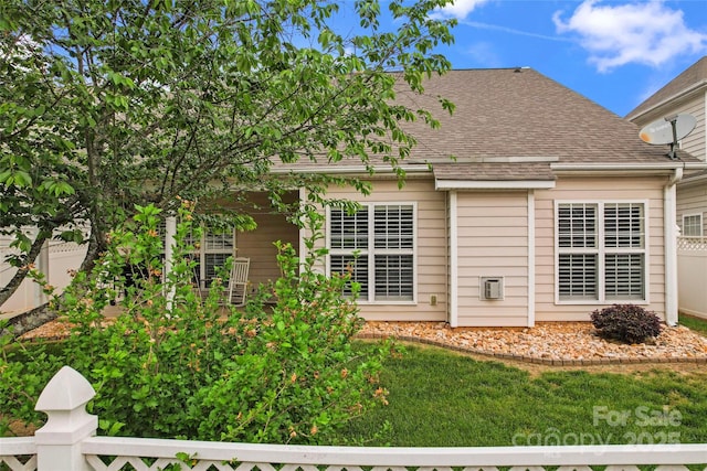 back of house featuring a shingled roof and fence