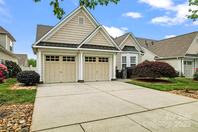 craftsman-style home featuring an attached garage, a standing seam roof, driveway, and metal roof