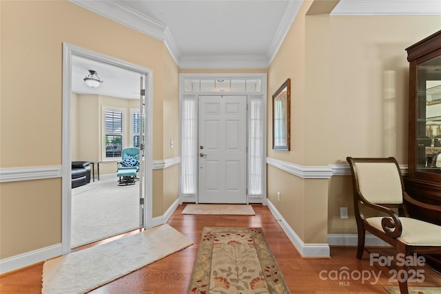 foyer with wood finished floors, crown molding, and baseboards