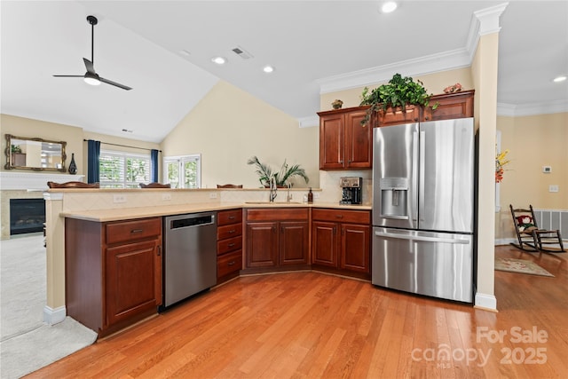 kitchen featuring light wood finished floors, stainless steel appliances, light countertops, a sink, and ceiling fan