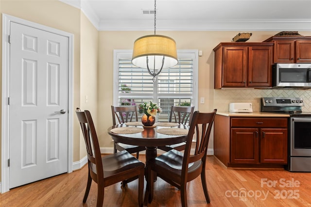 dining room with light wood-type flooring, visible vents, and ornamental molding