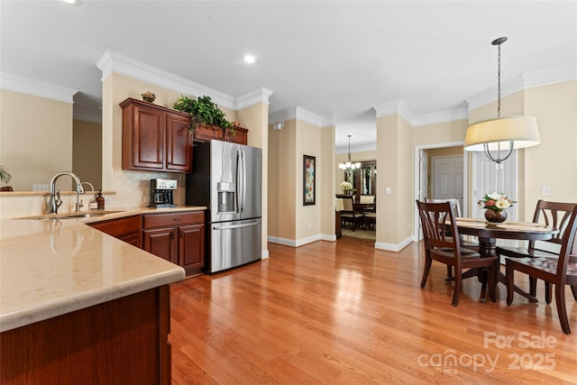 kitchen featuring crown molding, a sink, stainless steel fridge, light wood finished floors, and backsplash