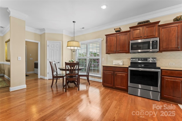kitchen with light wood finished floors, light countertops, ornamental molding, tasteful backsplash, and appliances with stainless steel finishes