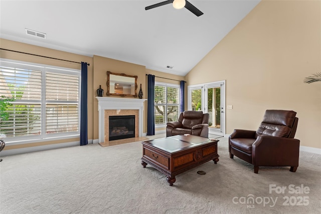 carpeted living room featuring high vaulted ceiling, a ceiling fan, a fireplace, baseboards, and visible vents