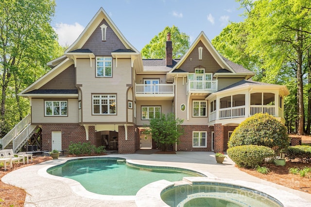 rear view of house featuring stairway, a chimney, a shingled roof, a patio, and brick siding
