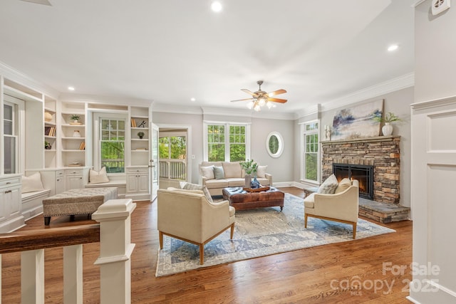 living area with ceiling fan, ornamental molding, wood finished floors, and a fireplace