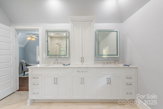 bathroom featuring vaulted ceiling, a sink, double vanity, and tiled shower
