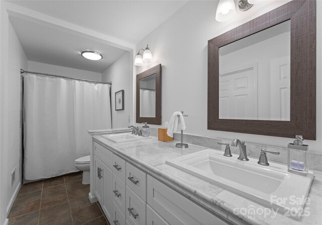 bathroom featuring toilet, double vanity, and tile patterned flooring