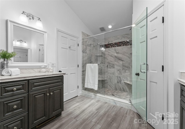full bathroom with vaulted ceiling, vanity, a stall shower, wood finished floors, and recessed lighting