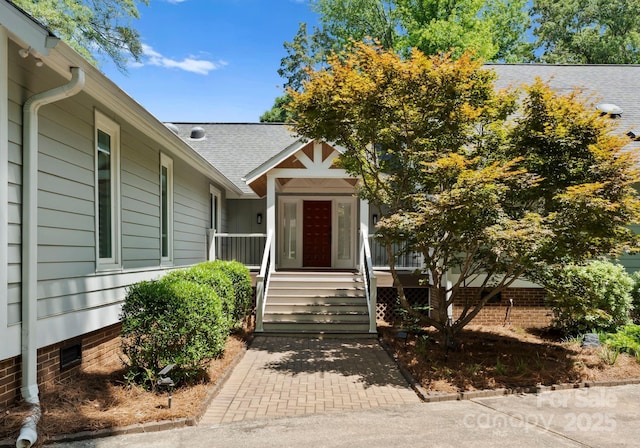 property entrance with roof with shingles and crawl space