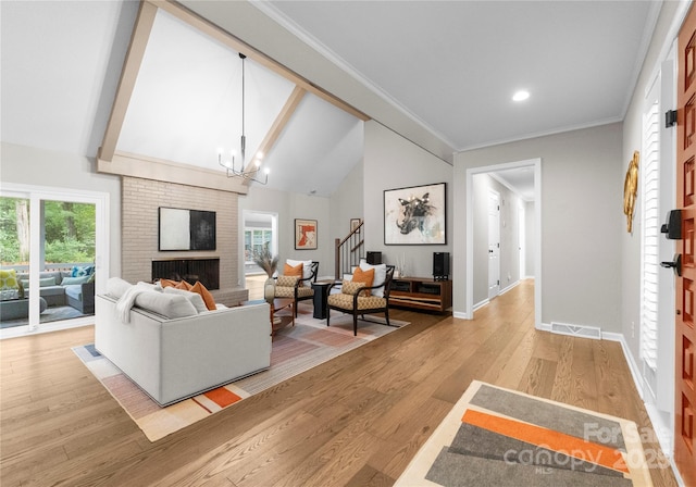 living room with stairway, a fireplace, baseboards, light wood-type flooring, and a chandelier