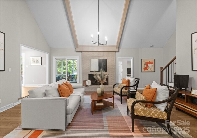 living area featuring beam ceiling, wood finished floors, stairway, a chandelier, and baseboards