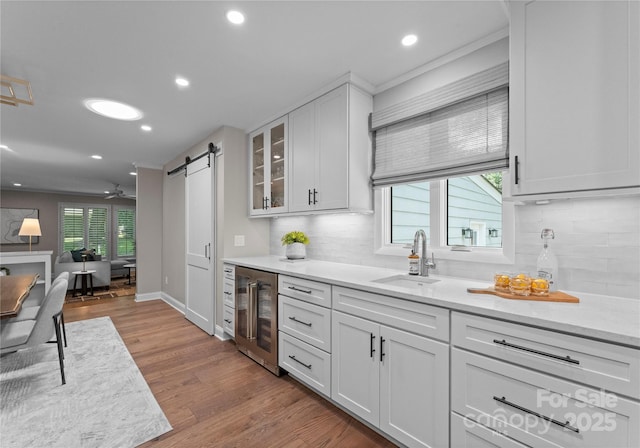 kitchen featuring wine cooler, a sink, healthy amount of natural light, a barn door, and recessed lighting