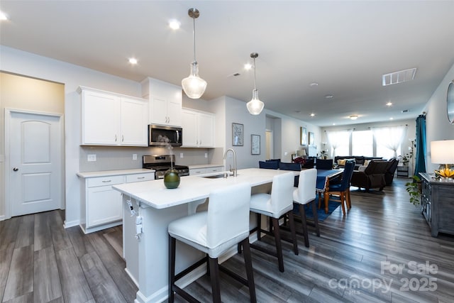 3100 Cheyney Park Dr, Charlotte, NC 28269 - kitchen featuring visible vents, light countertops, a sink, stainless steel appliances, and a breakfast bar area