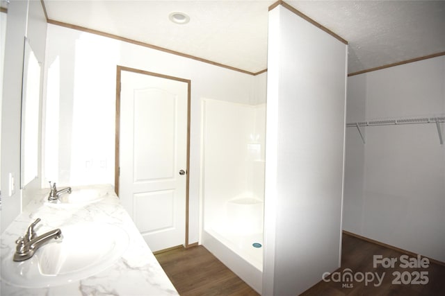828 Long Bow Rd, Salisbury, NC 28144 - full bathroom featuring wood finished floors, double vanity, crown molding, a walk in closet, and a shower