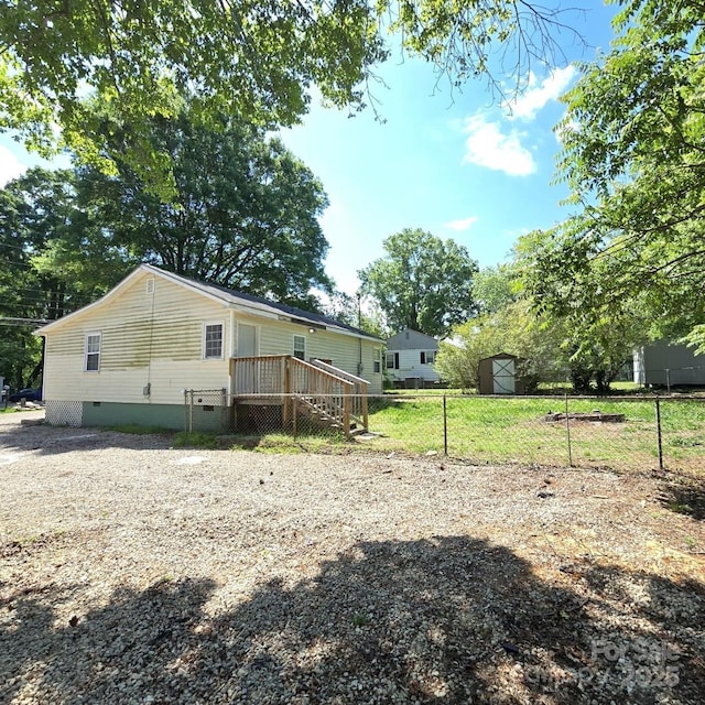 exterior space with crawl space, an outbuilding, a storage shed, a deck, and fence