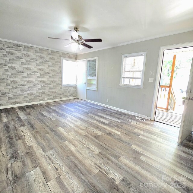 unfurnished room featuring crown molding, a ceiling fan, visible vents, and wood finished floors