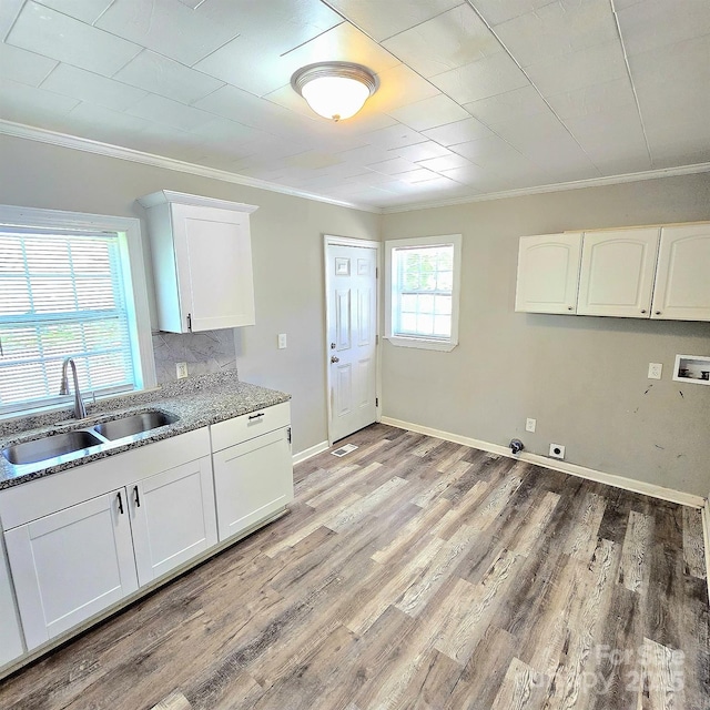 kitchen with light stone countertops, a sink, crown molding, light wood-style flooring, and white cabinets