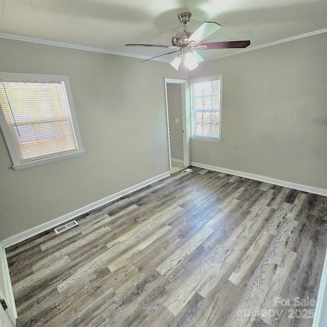 unfurnished bedroom featuring wood finished floors, ornamental molding, baseboards, visible vents, and a ceiling fan