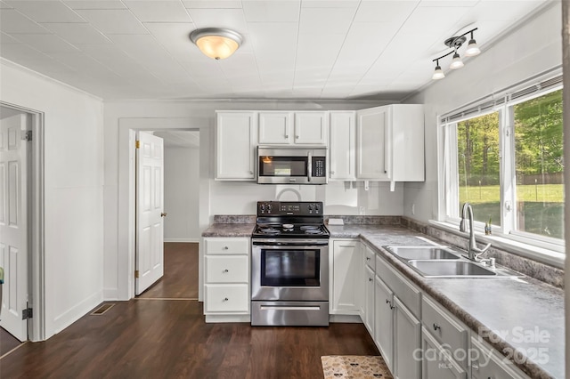 kitchen with dark wood-type flooring, white cabinetry, appliances with stainless steel finishes, light countertops, and a sink