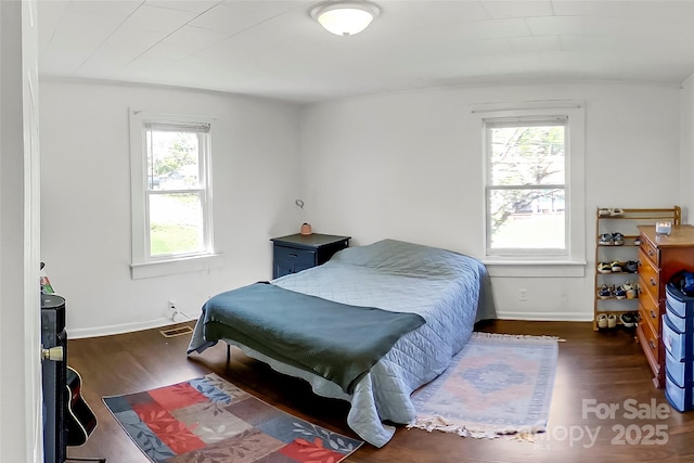 bedroom featuring wood finished floors, baseboards, and multiple windows
