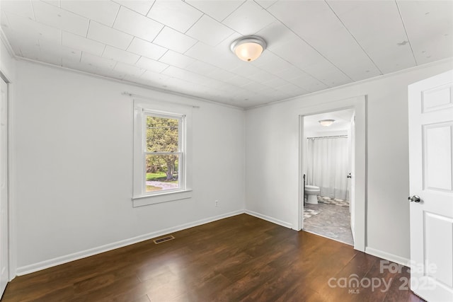 unfurnished bedroom featuring crown molding, visible vents, connected bathroom, and wood finished floors