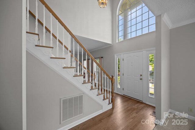 9000 Stourbridge Dr, Huntersville, NC 28078 - foyer featuring crown molding, a high ceiling, stairs, wood finished floors, and visible vents