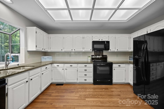 9000 Stourbridge Dr, Huntersville, NC 28078 - kitchen featuring a sink, dark stone counters, white cabinetry, light wood-type flooring, and black appliances