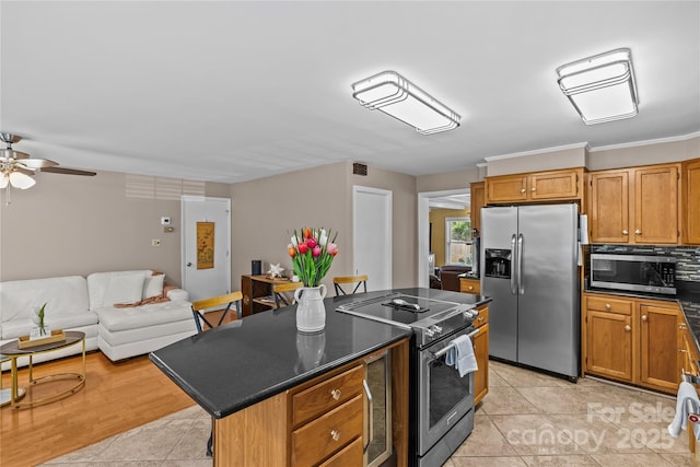 6035 Idlebrook Dr, Charlotte, NC 28212 - kitchen featuring appliances with stainless steel finishes, dark countertops, a kitchen island, a ceiling fan, and open floor plan