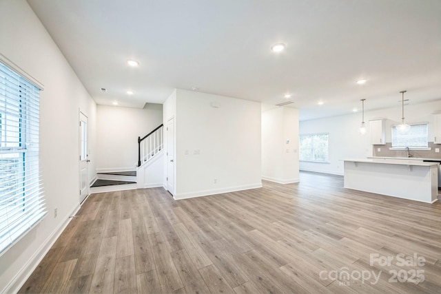 81 Walnut Springs Dr Unit 22-D, Asheville, NC 28804 - unfurnished living room featuring recessed lighting, stairway, light wood-style flooring, and a sink