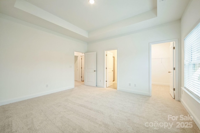 81 Walnut Springs Dr Unit 22-D, Asheville, NC 28804 - unfurnished bedroom featuring baseboards, a spacious closet, a tray ceiling, ensuite bath, and light carpet