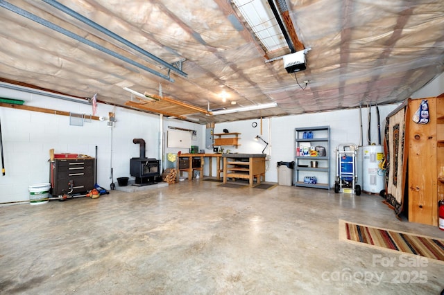 15 Heather Ln, Fairview, NC 28730 - garage featuring electric water heater, concrete block wall, a workshop area, a wood stove, and a garage door opener