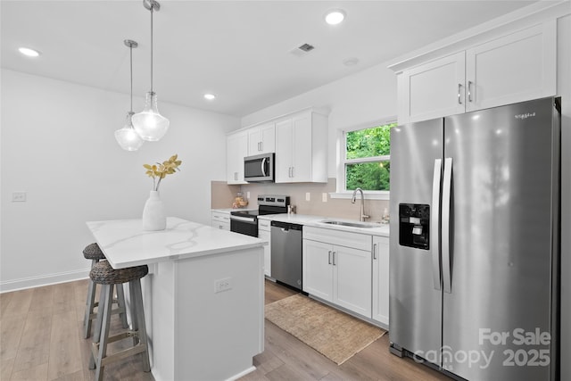 184 Cherry Springs Ln Unit 1-B, Asheville, NC 28804 - kitchen with stainless steel appliances, a center island, white cabinets, light wood-style floors, and decorative light fixtures