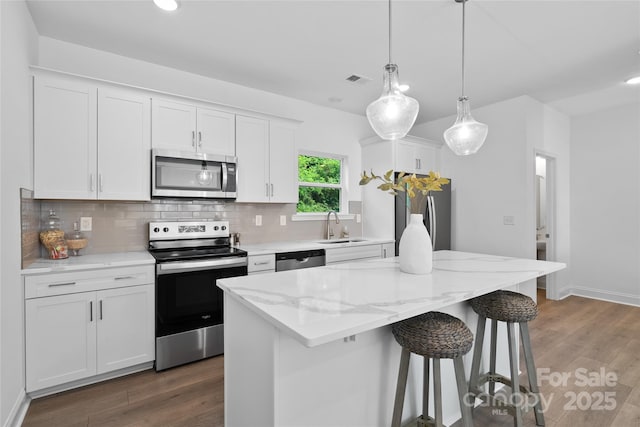 184 Cherry Springs Ln Unit 1-B, Asheville, NC 28804 - kitchen with stainless steel appliances, backsplash, white cabinetry, a breakfast bar, and dark wood finished floors