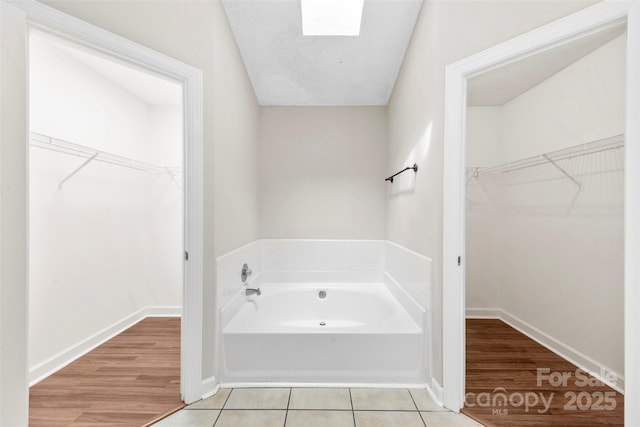 13324 Kintyre Ct, Matthews, NC 28105 - full bathroom featuring a garden tub, a skylight, a spacious closet, and tile patterned flooring