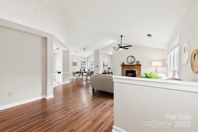 13324 Kintyre Ct, Matthews, NC 28105 - living room featuring a ceiling fan, dark wood-type flooring, lofted ceiling, a brick fireplace, and baseboards