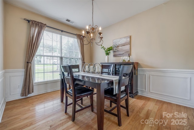 dining room with visible vents, a wainscoted wall, light wood finished floors, and a notable chandelier
