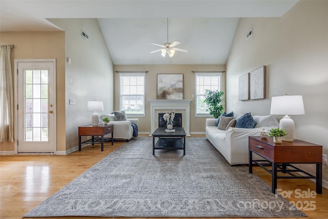 living area with wood finished floors, visible vents, a ceiling fan, and vaulted ceiling