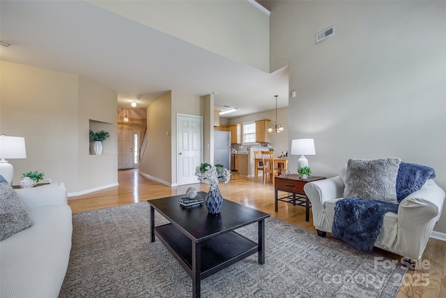 living area featuring light wood-style flooring, baseboards, and visible vents