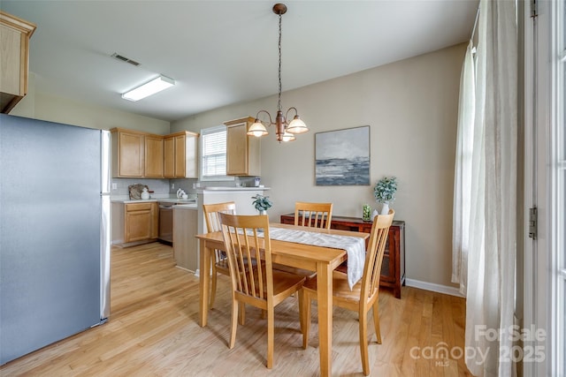 dining space featuring visible vents, light wood-type flooring, and an inviting chandelier