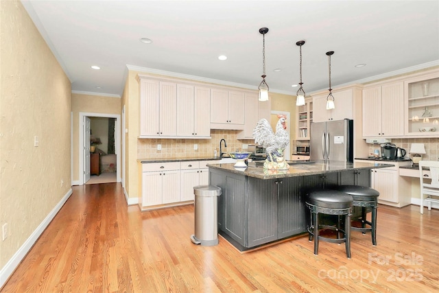729 Lochaven Rd, Waxhaw, NC 28173 - kitchen with appliances with stainless steel finishes, tasteful backsplash, a center island with sink, light wood-type flooring, and crown molding