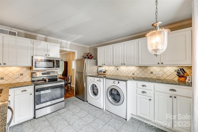 4607 Hedgemore Dr Unit H, Charlotte, NC 28209 - kitchen featuring washer and clothes dryer, dark stone countertops, white cabinetry, crown molding, and appliances with stainless steel finishes