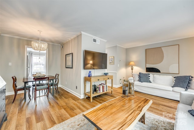 4607 Hedgemore Dr Unit H, Charlotte, NC 28209 - living area with light wood-type flooring, baseboards, visible vents, a notable chandelier, and crown molding