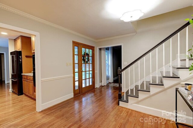 foyer entrance with stairway, light wood-type flooring, french doors, baseboards, and ornamental molding